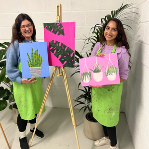 two women holding plant paintings
