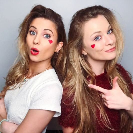two women with red hearts painted on their faces