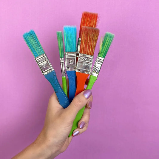 Hand holding multi-coloured paintbrushes
