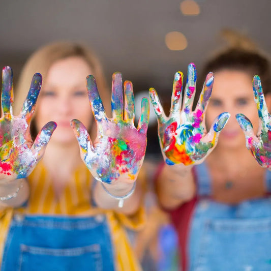 two women with paint splattered hands