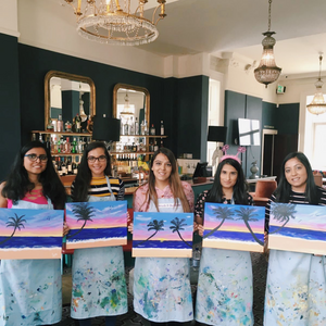 women holding their palm tree sunset paintings for hen do celebration