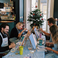 colleagues painting canvases with Christmas tree in background