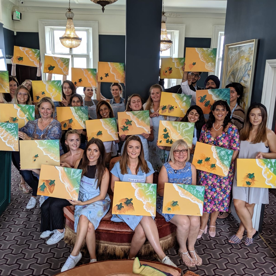 picture of group smiling holding paintings of sea turtles