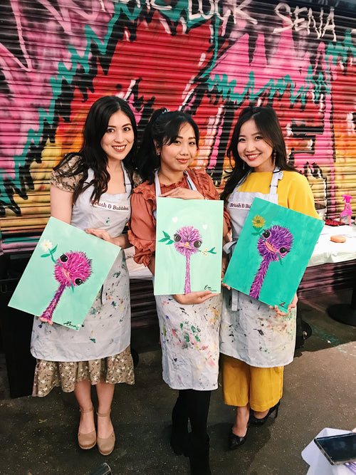 three women hold paintings of emus after art-themed birthday