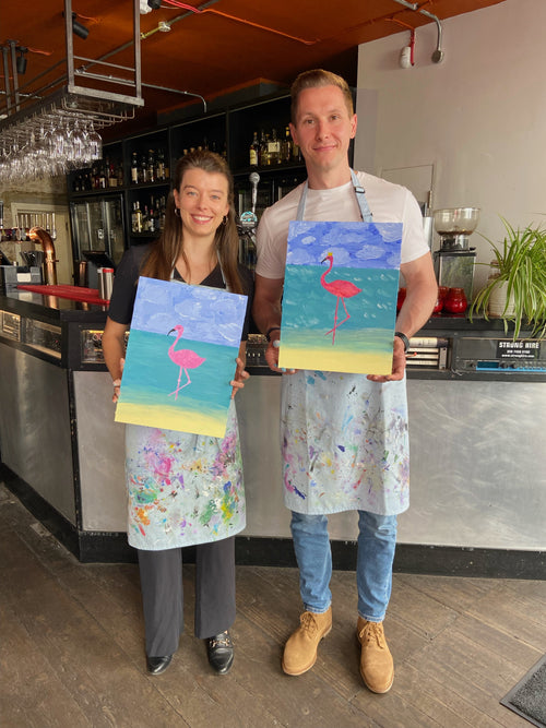 a couple holds paintings of flamingos after paint and sip date night