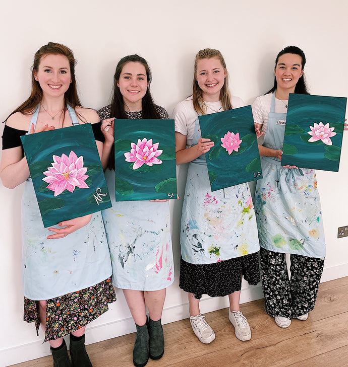 four women holding lotus flower paintings